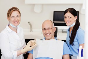 Dentist With Teeth Model And Male Patient